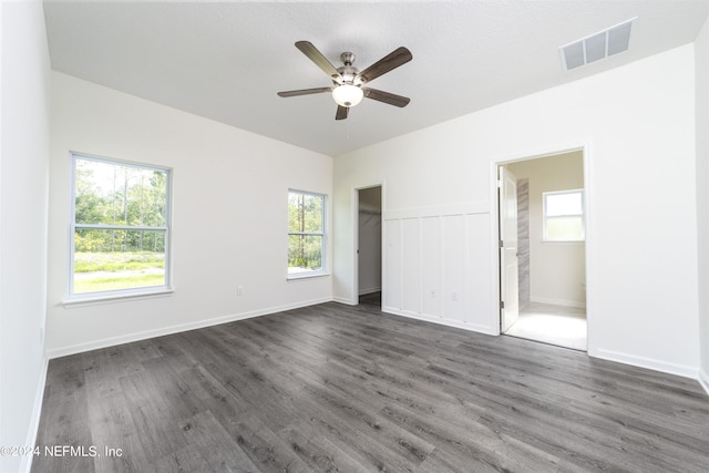 unfurnished bedroom with ceiling fan, dark wood-type flooring, and ensuite bath