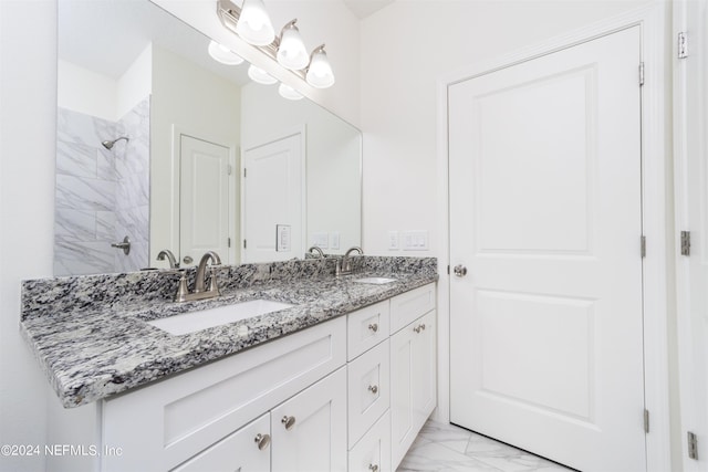 bathroom with a tile shower and vanity