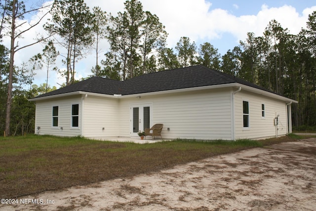 back of property featuring a yard, french doors, and a patio