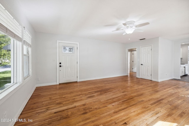 unfurnished living room featuring light wood-type flooring, ceiling fan, and a wealth of natural light