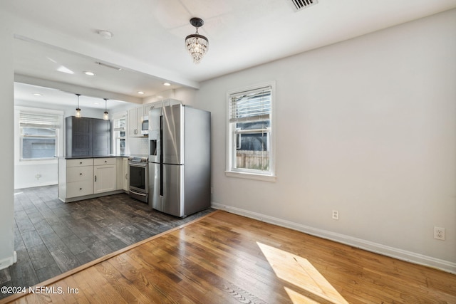 kitchen featuring white cabinets, dark hardwood / wood-style floors, decorative light fixtures, and appliances with stainless steel finishes