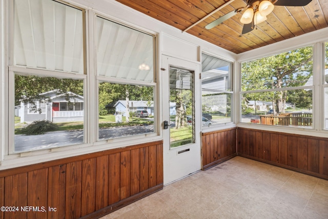 unfurnished sunroom featuring wood ceiling, ceiling fan, and a healthy amount of sunlight