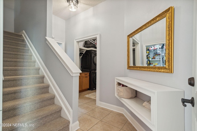 entryway with stacked washer and clothes dryer and light tile patterned floors