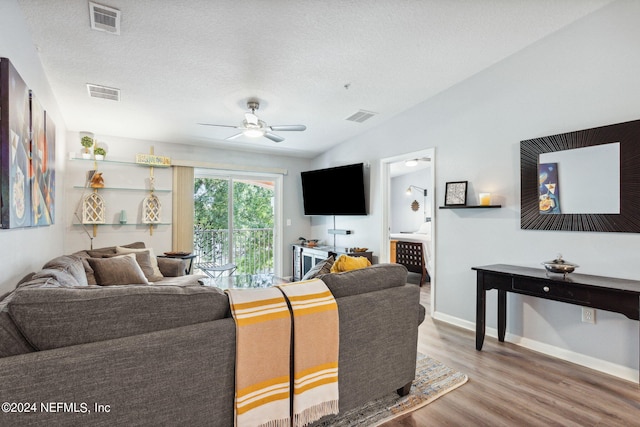 living room featuring a textured ceiling, wood-type flooring, and ceiling fan