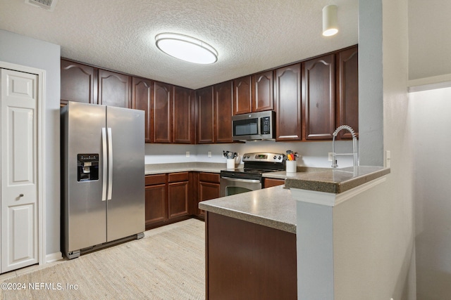 kitchen with stainless steel appliances, a textured ceiling, sink, and kitchen peninsula