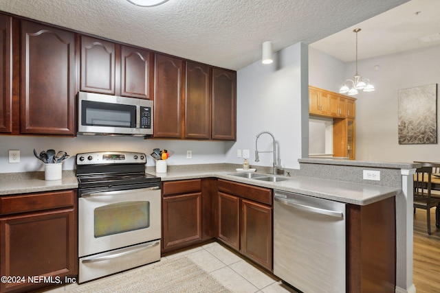 kitchen featuring a chandelier, a textured ceiling, kitchen peninsula, stainless steel appliances, and sink