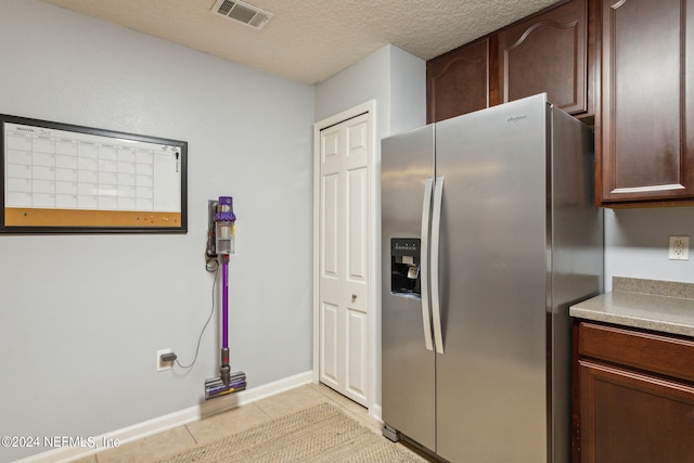 kitchen with light tile patterned flooring, a textured ceiling, and stainless steel fridge with ice dispenser