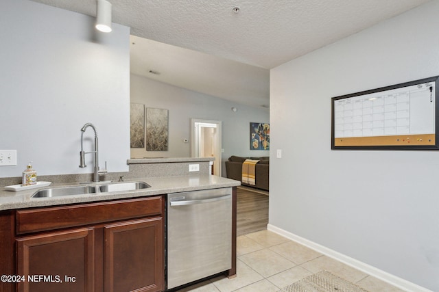 kitchen with lofted ceiling, light hardwood / wood-style flooring, a textured ceiling, stainless steel dishwasher, and sink