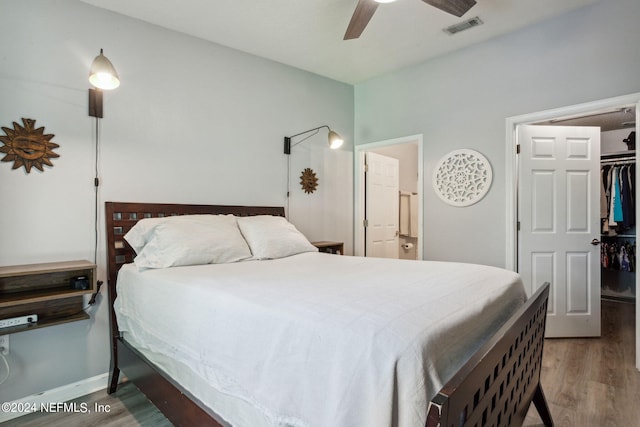 bedroom with a spacious closet, ceiling fan, light hardwood / wood-style floors, and a closet