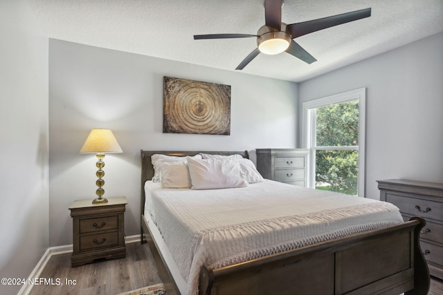 bedroom with dark hardwood / wood-style floors, a textured ceiling, and ceiling fan