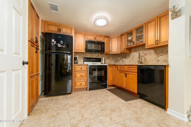 kitchen featuring black appliances, light stone counters, sink, decorative backsplash, and light tile patterned flooring