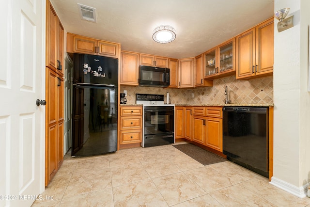 kitchen featuring visible vents, backsplash, black appliances, brown cabinetry, and glass insert cabinets