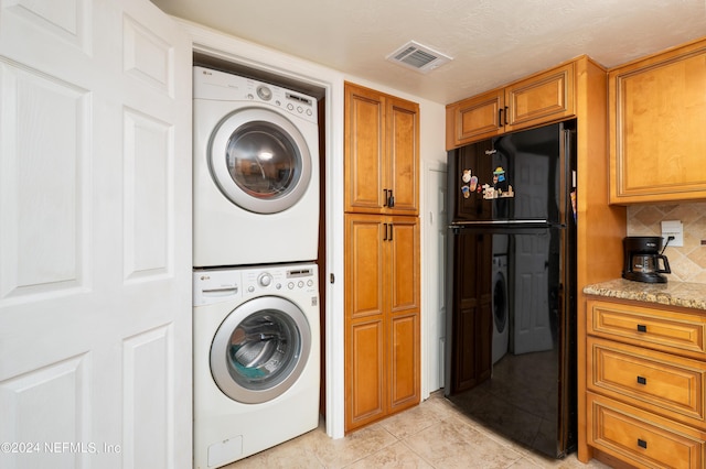 laundry area featuring laundry area, stacked washer and clothes dryer, visible vents, and light tile patterned floors