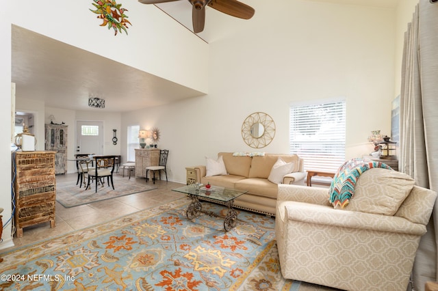 tiled living room featuring baseboards, ceiling fan, and a high ceiling