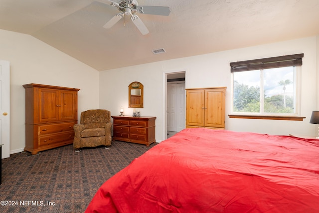 bedroom with visible vents, vaulted ceiling, a ceiling fan, and dark colored carpet