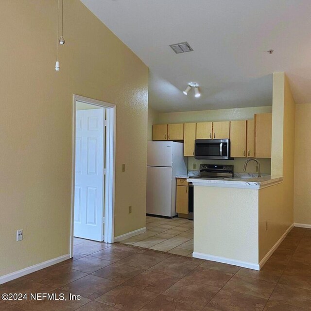 kitchen featuring light brown cabinetry, white fridge, dark tile patterned flooring, kitchen peninsula, and electric range oven