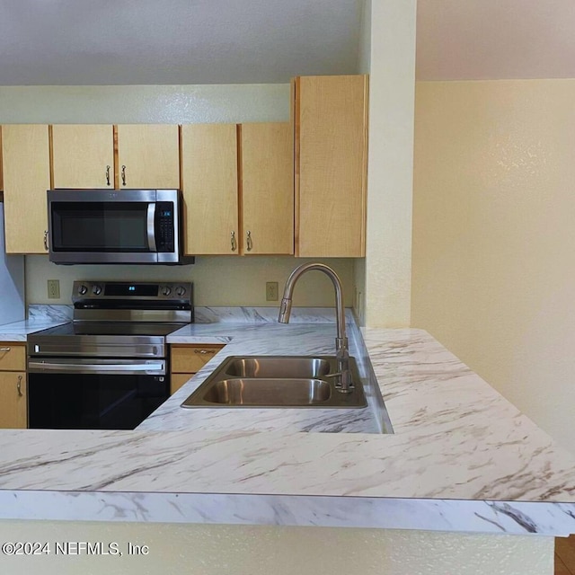 kitchen featuring sink, stainless steel appliances, light brown cabinetry, and kitchen peninsula