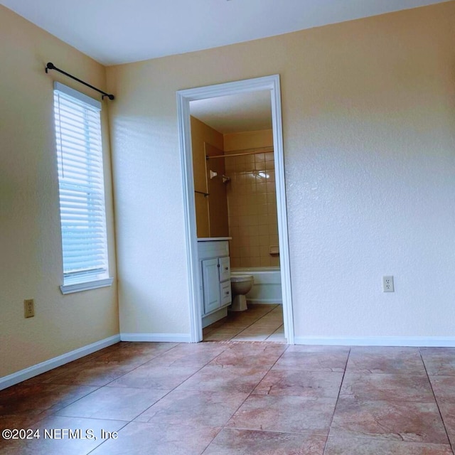 unfurnished bedroom featuring connected bathroom, a walk in closet, and light tile patterned flooring