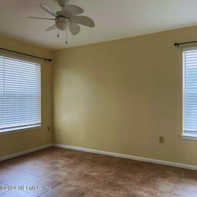 tiled empty room featuring plenty of natural light and ceiling fan