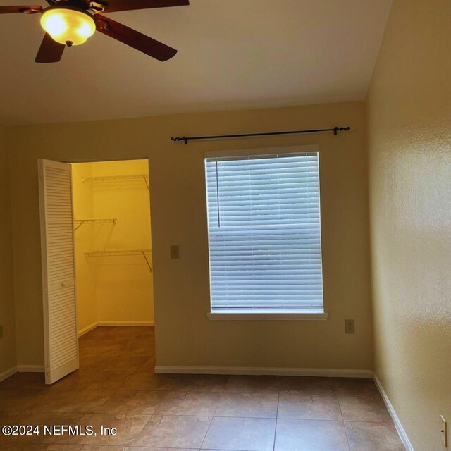 empty room featuring ceiling fan, a wealth of natural light, and tile patterned flooring