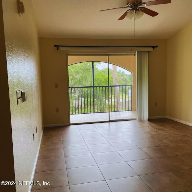 tiled empty room featuring ceiling fan and baseboards