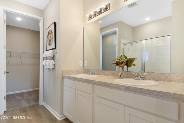 bathroom with a shower with shower door, hardwood / wood-style flooring, and vanity