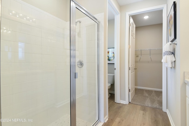 bathroom with toilet, vanity, wood-type flooring, and an enclosed shower