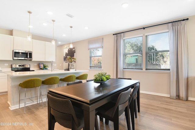 dining space featuring light wood-type flooring and sink