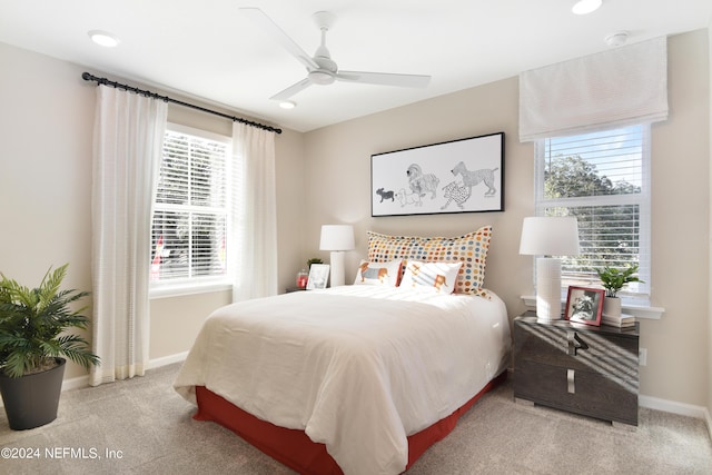 bedroom featuring ceiling fan, light colored carpet, and multiple windows