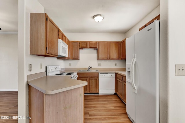 kitchen with white appliances, light wood-type flooring, sink, and kitchen peninsula