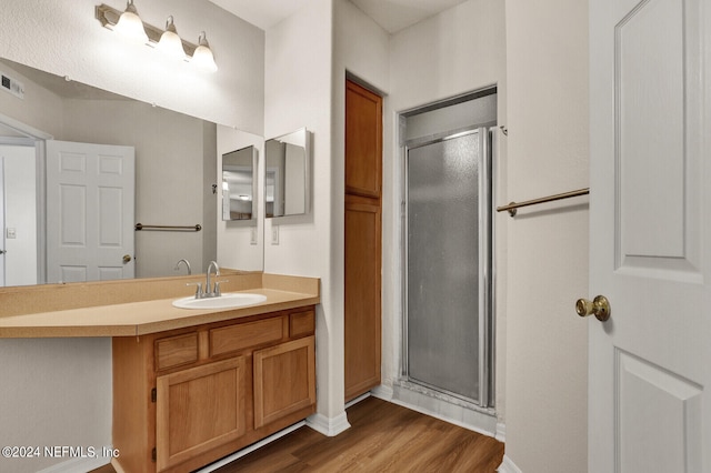 bathroom with vanity, a shower with shower door, and hardwood / wood-style floors