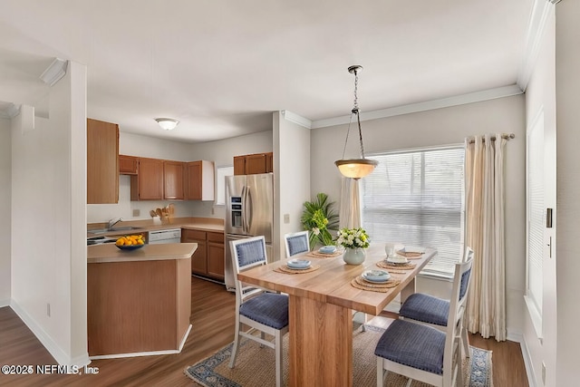 kitchen with dark hardwood / wood-style floors, crown molding, white dishwasher, stainless steel fridge, and hanging light fixtures