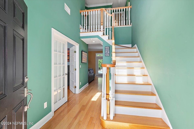 stairs with light hardwood / wood-style flooring and a high ceiling