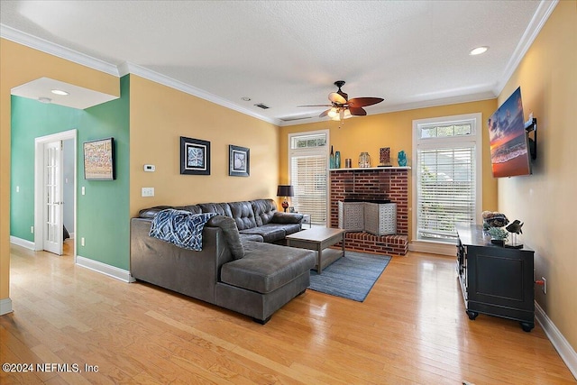 living room with light wood-type flooring, ceiling fan, ornamental molding, and a textured ceiling