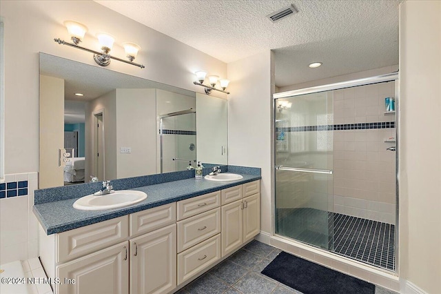 bathroom featuring dual vanity, walk in shower, tile patterned flooring, and a textured ceiling