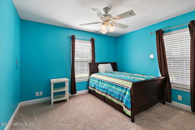 bedroom with a textured ceiling, ceiling fan, and light colored carpet