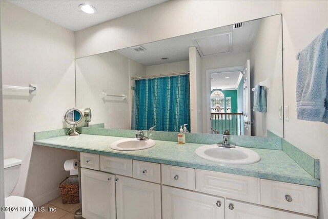 bathroom with dual vanity, tile patterned floors, and toilet