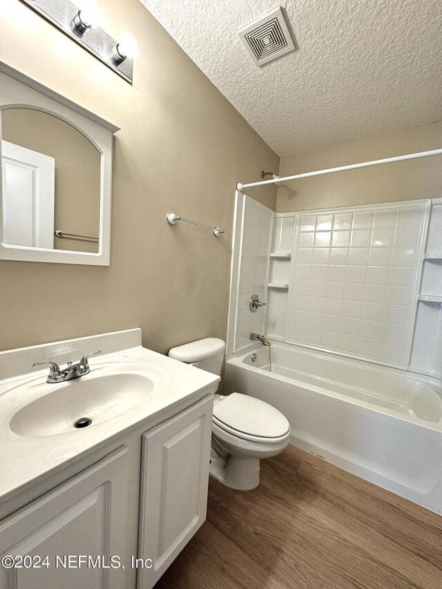 full bathroom with a textured ceiling, shower / bath combination, toilet, vanity, and wood-type flooring