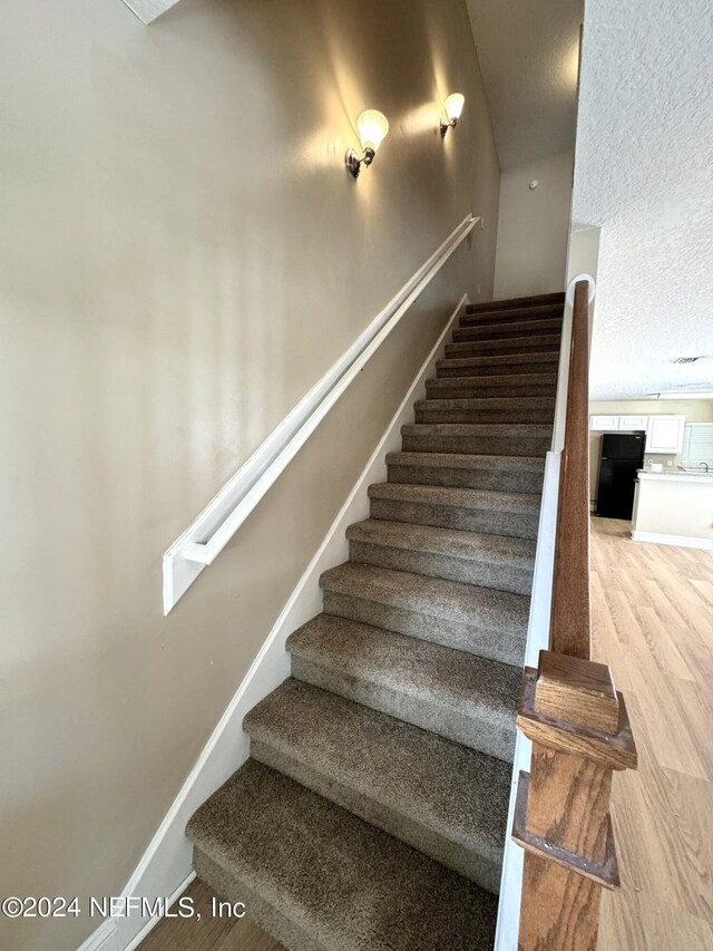 stairway featuring light hardwood / wood-style flooring and a textured ceiling