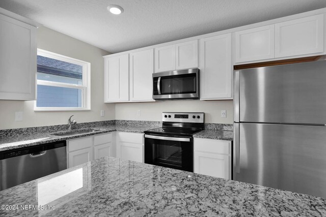 kitchen with sink, light stone countertops, white cabinets, and stainless steel appliances