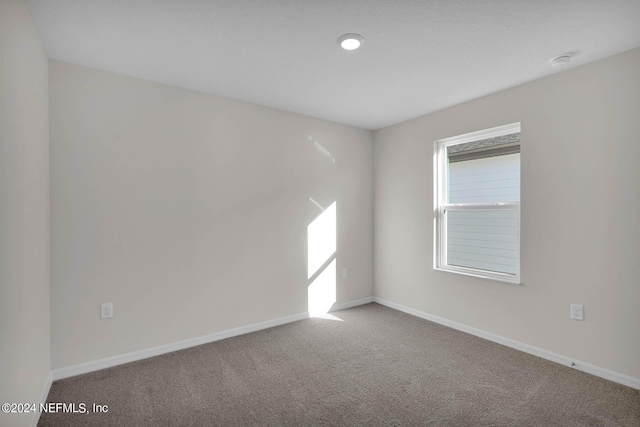 carpeted spare room featuring baseboards