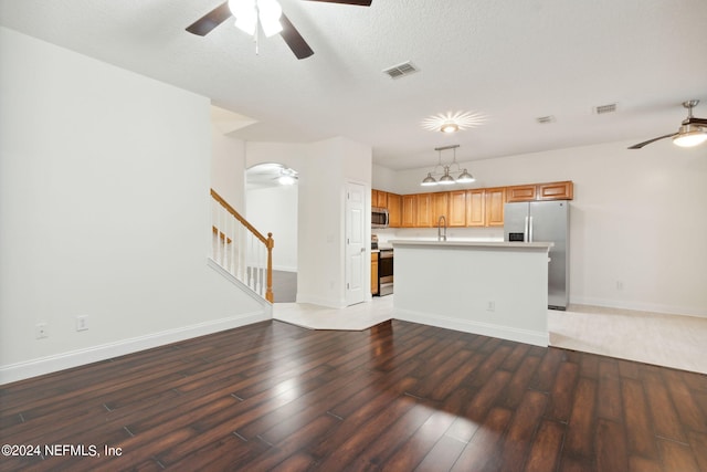 unfurnished living room with ceiling fan, sink, a textured ceiling, and hardwood / wood-style flooring