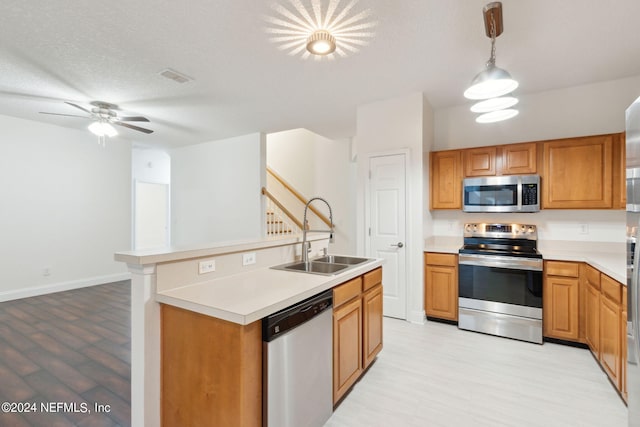 kitchen with appliances with stainless steel finishes, a kitchen island with sink, decorative light fixtures, a textured ceiling, and sink