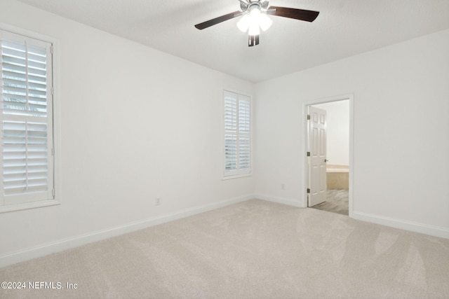 unfurnished bedroom featuring ceiling fan, light carpet, and connected bathroom