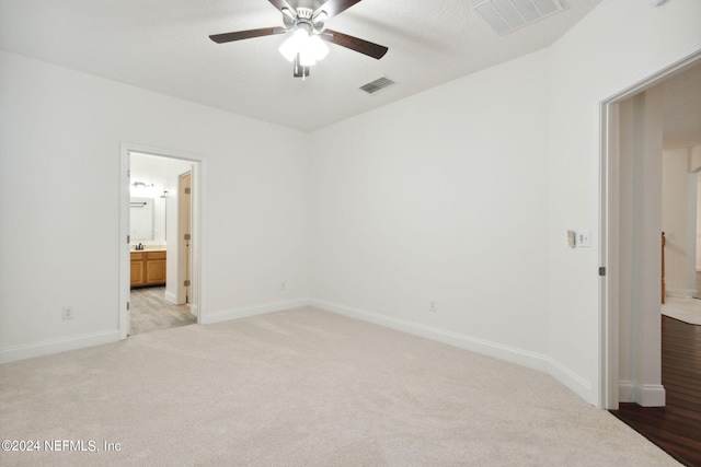 unfurnished bedroom with light carpet, ceiling fan, and ensuite bath