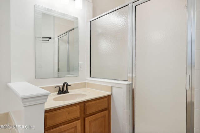 bathroom featuring a shower with shower door and vanity