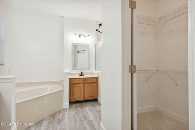 bathroom featuring vanity, a washtub, and hardwood / wood-style floors