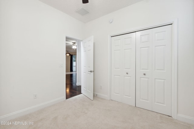 unfurnished bedroom featuring ceiling fan, a closet, and light carpet