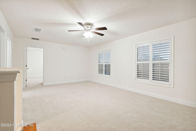 carpeted empty room with ceiling fan and a textured ceiling