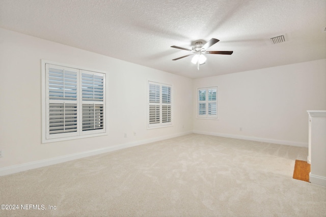 unfurnished room featuring ceiling fan, light colored carpet, and a textured ceiling